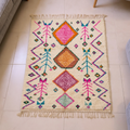 Azilal ivory wool rug with orange, pink and teal diamonds, zigzags and bird motifs, shown flat