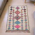 Azilal ivory wool rug with an all-over pink, blue and orange diamond field, shown flat