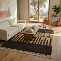 Black and camel Beni Ourain rug in a warm living room with neutral sofa and leather chair