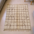 Mrirt ivory wool rug with brown grid lines and Amazigh tribal symbols, shown flat