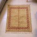Mrirt golden-camel wool rug with terracotta diamond border, shown flat